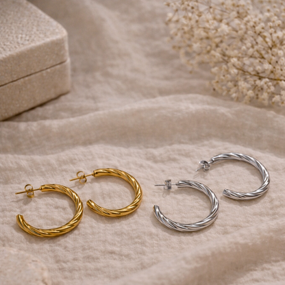 Gold and silver hoop earrings on a soft beige fabric background