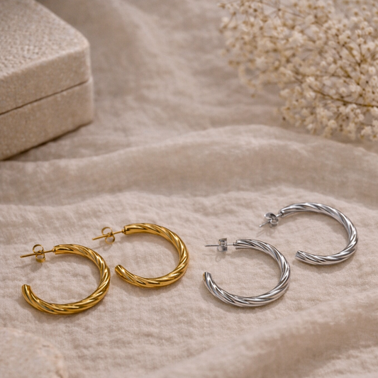 Gold and silver hoop earrings on a soft beige fabric background