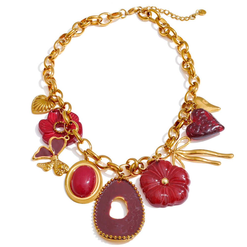 Gold statement necklace with red charm pieces on a white background