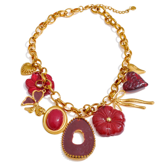 Gold statement necklace with red charm pieces on a white background