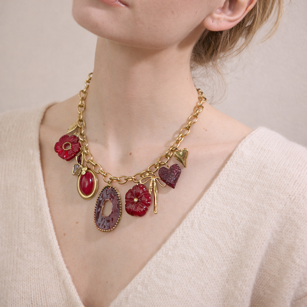 Gold necklace with red gemstone charms worn by a person