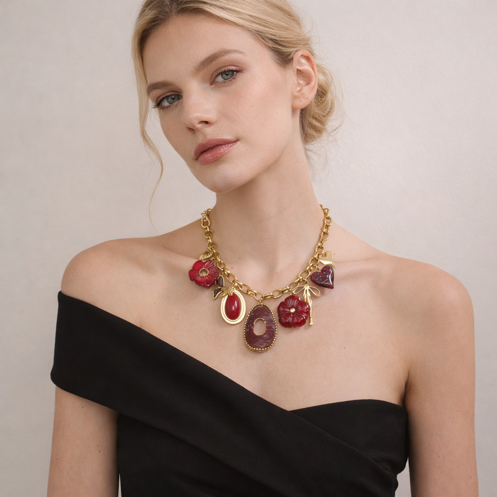 Woman wearing a gold necklace with red and purple pendants on a plain background