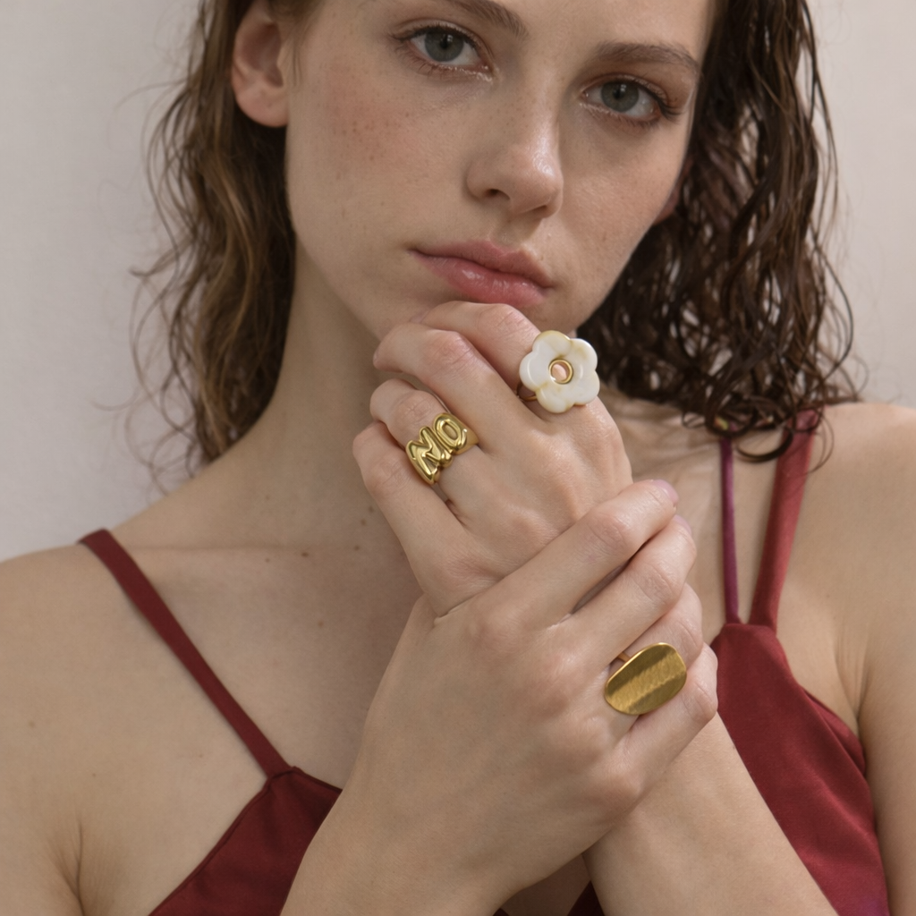 Woman wearing gold rings with a neutral background