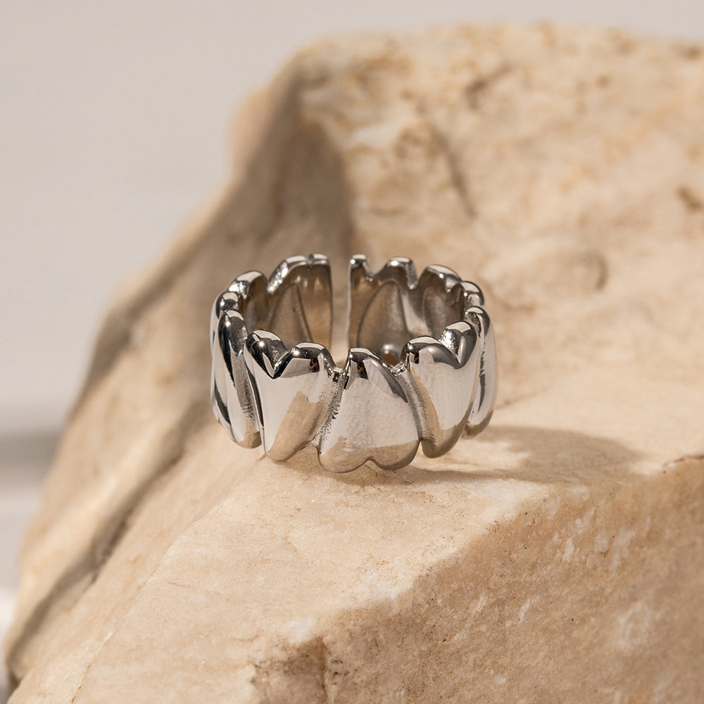 Silver ring with a unique design on a beige stone surface