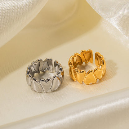 Two heart-shaped rings, one silver and one gold, on a beige fabric background.