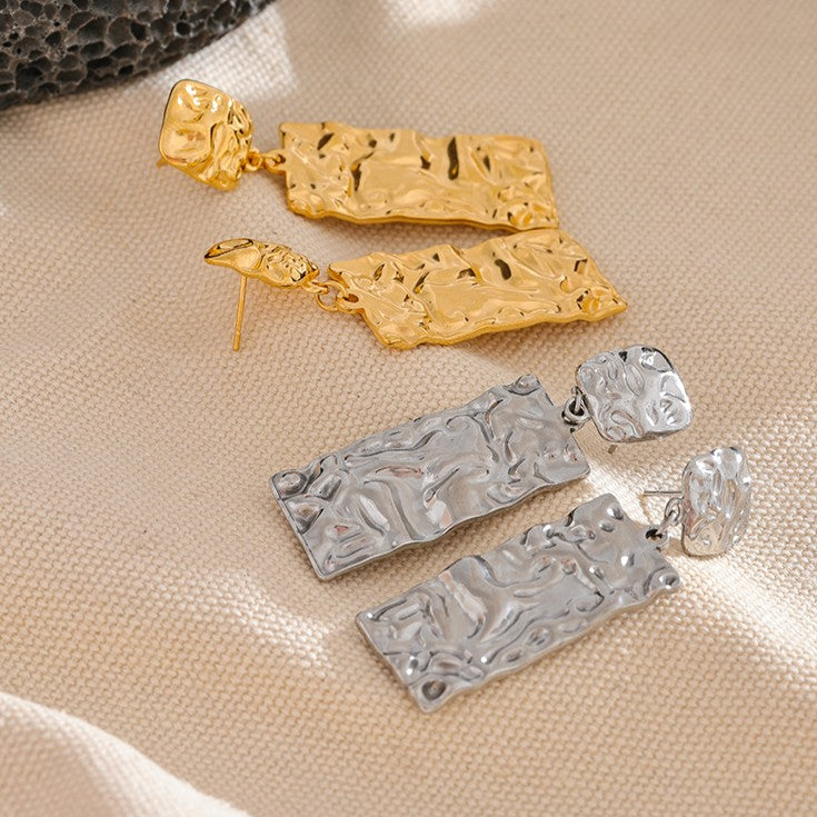 Gold and silver earrings on a beige fabric background