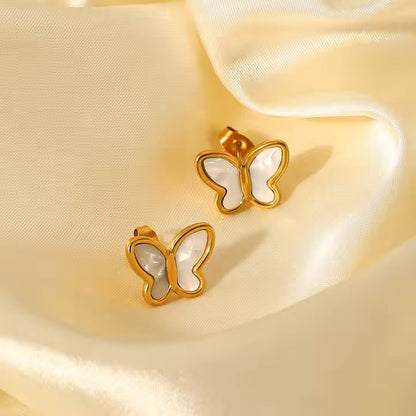 Gold stainless steel butterfly earrings on a soft yellow fabric background