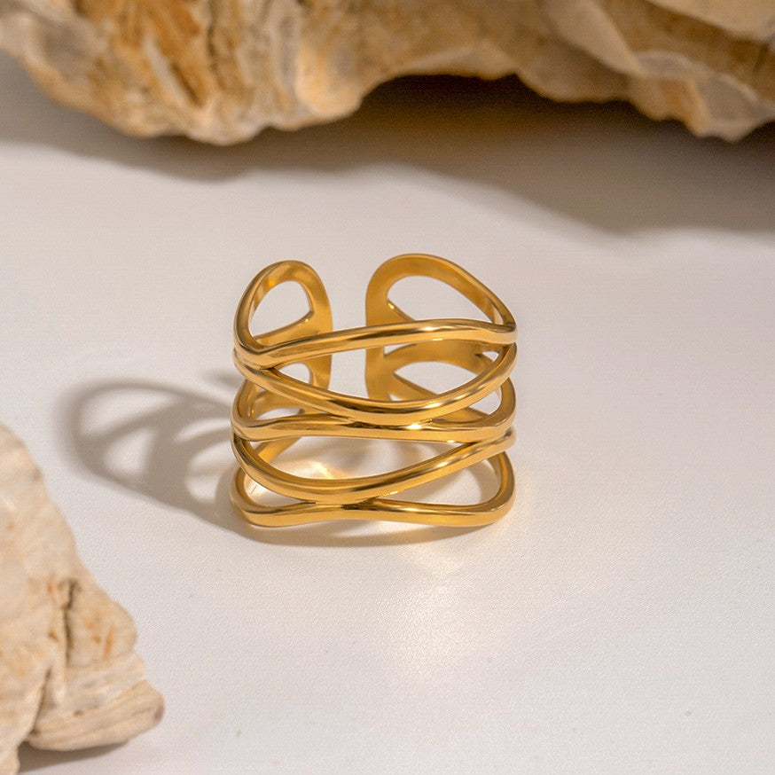 Gold ring with a textured design on a light background with seashells.