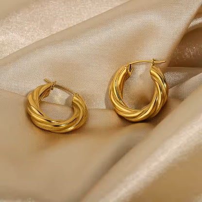 Gold stainless steel hoop earrings on a beige satin background