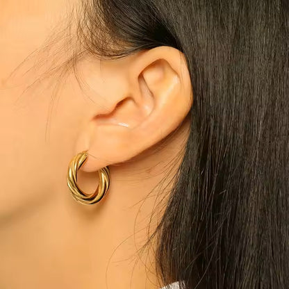 Close-up of an ear wearing a gold hoop earring with dark hair.