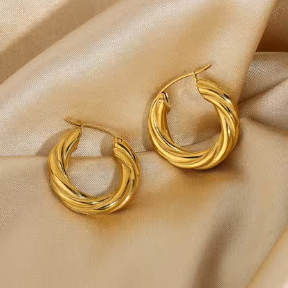 Gold stainless steel hoop earrings on a beige satin background