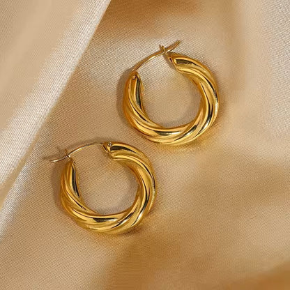 Gold stainless steel hoop earrings on a beige fabric background