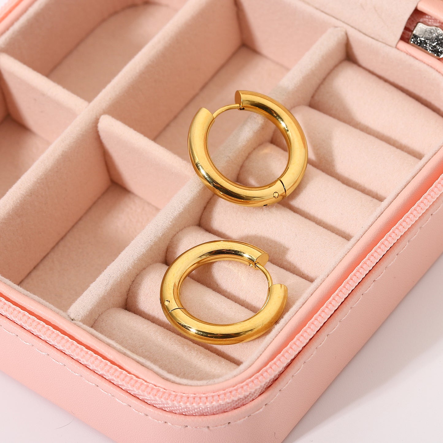 Gold hoop earrings in a pink jewelry box