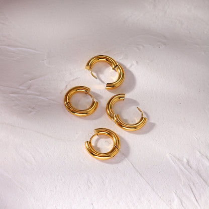 Gold waterproof hoop earrings on a textured white surface