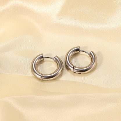 Pair of minimalist silver hoop earrings on a beige fabric background
