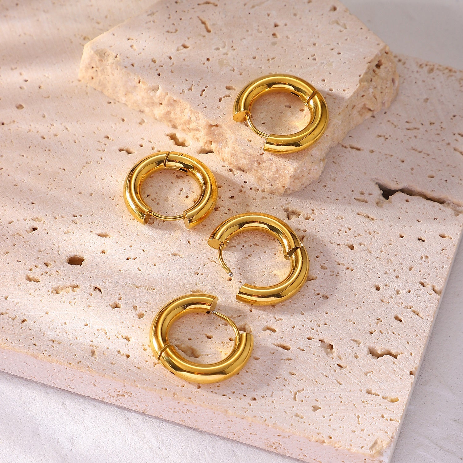 Gold affordable hoop earrings on a textured stone surface