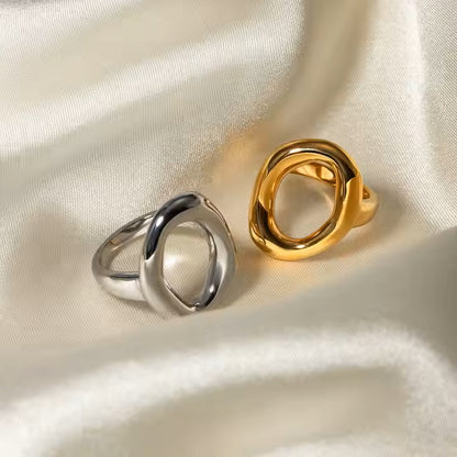 Two stainless steel rings, one silver and one gold, on a satin surface
