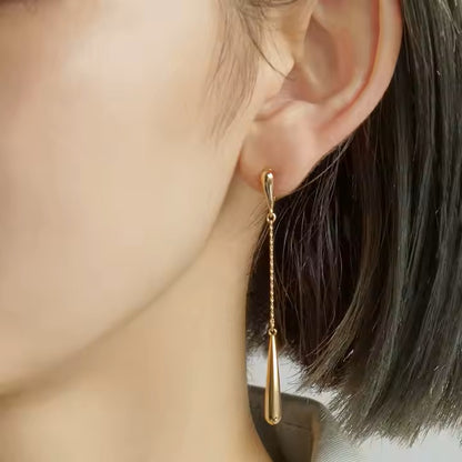 Gold stainless steel earring worn by a person with blurred background