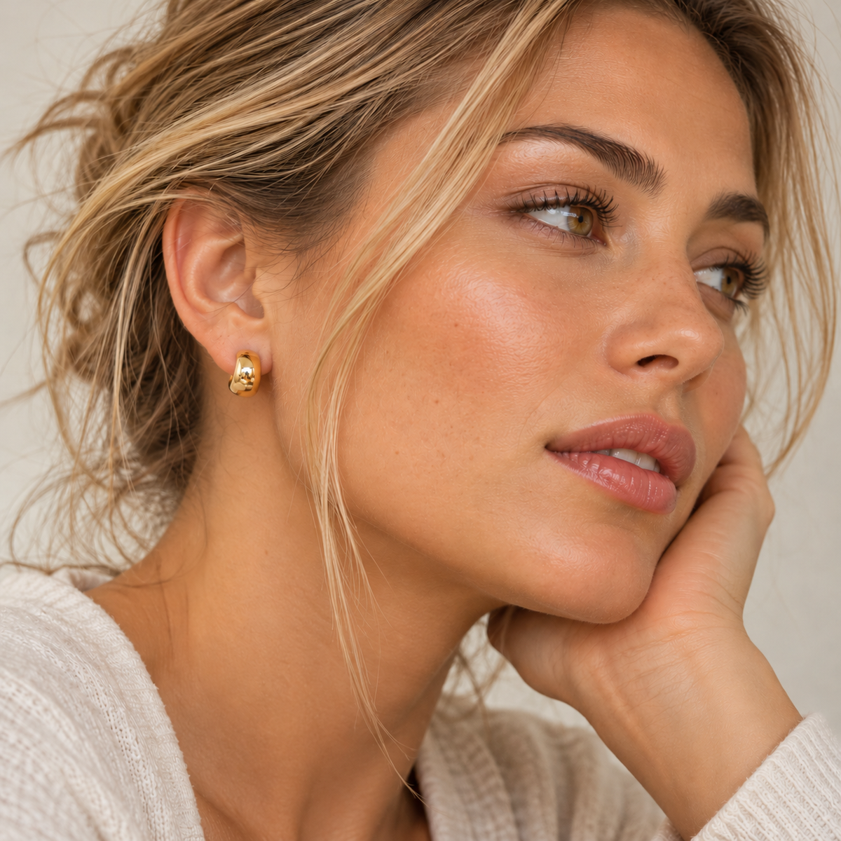 Small gold huggie hoop earrings in waterproof stainless steel, featuring a wide, rounded shape and polished finish, Pola Grace.