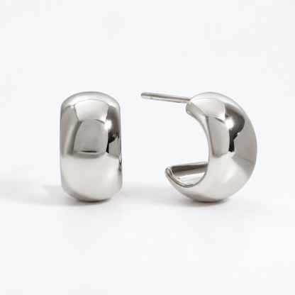 Small silver huggie hoop earrings in waterproof stainless steel, featuring a wide, rounded shape and polished finish, Pola Grace.
