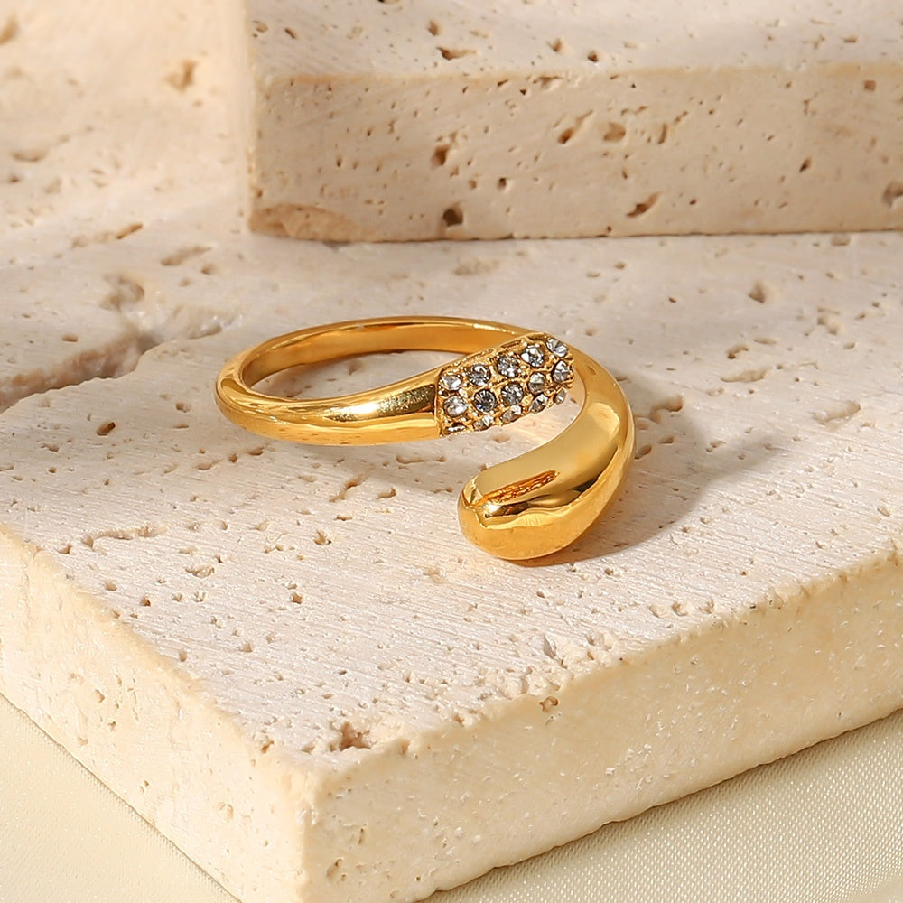 Gold ring with a decorative design on a textured beige surface