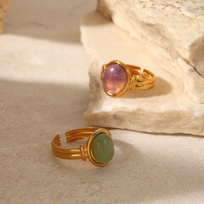 Two gold rings with gemstones on a stone surface