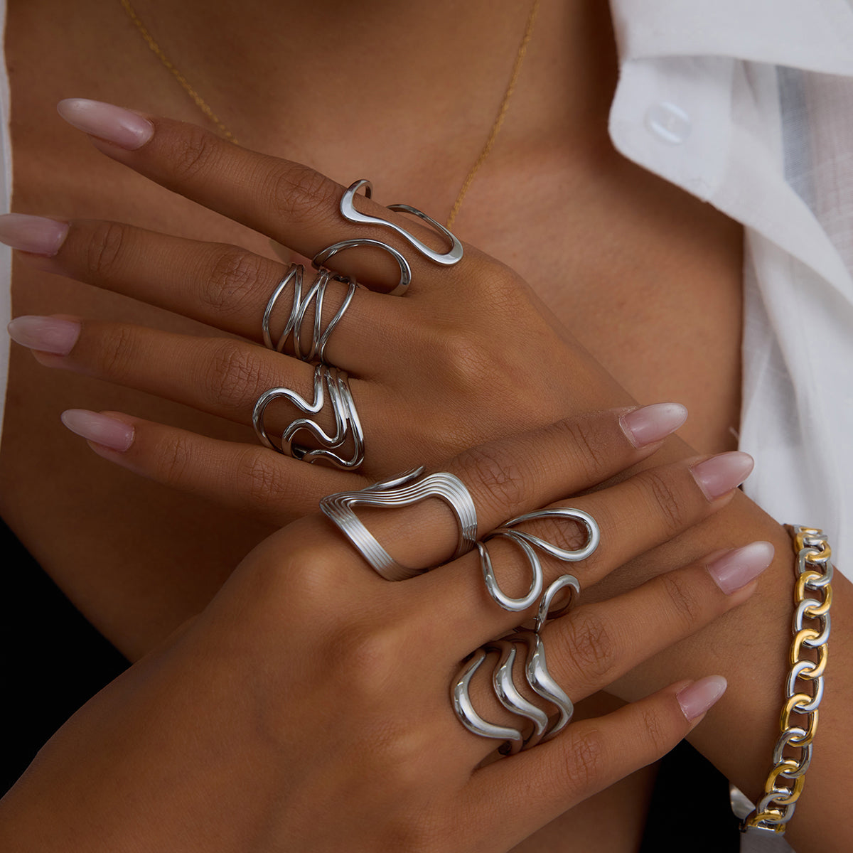 Close-up of hands wearing multiple silver rings with a blurred background