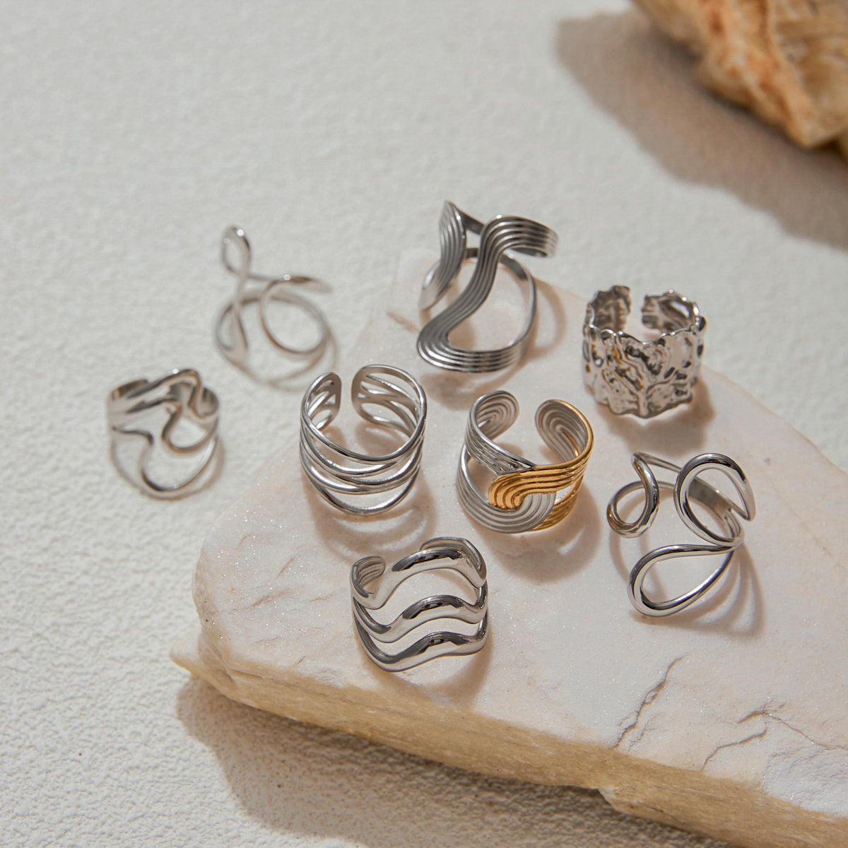 Set of silver and gold tarnish-free rings on a stone surface