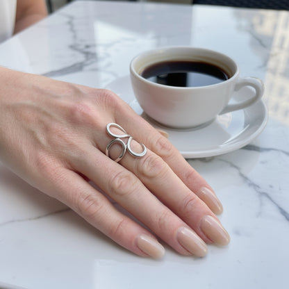 Hand wearing a silver waterproof ring with a cup of coffee on a marble surface