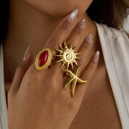 Gold rings with red stone and sun design on a hand