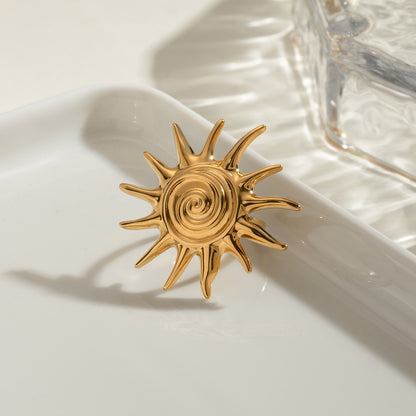 Gold sun-shaped ring on a white surface