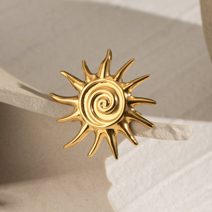 Gold sun-shaped statement ring on a beige surface