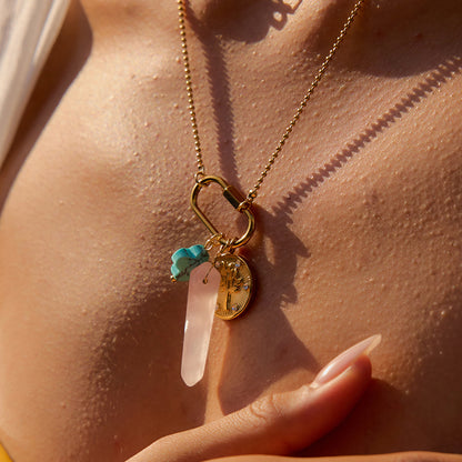 Necklace with a pendant featuring a turquoise stone and clear crystal on a person's neck.