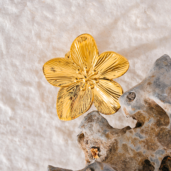 Gold flower-shaped ring on a textured surface