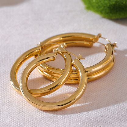 Gold hoop earrings on a light pink fabric background