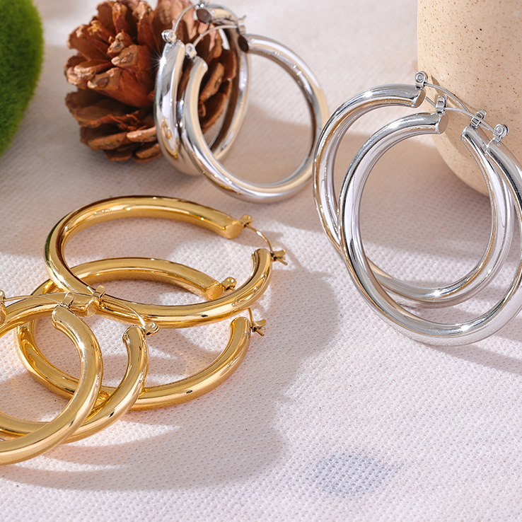 silver and gold stainless steel hoop earrings on aesthetic background