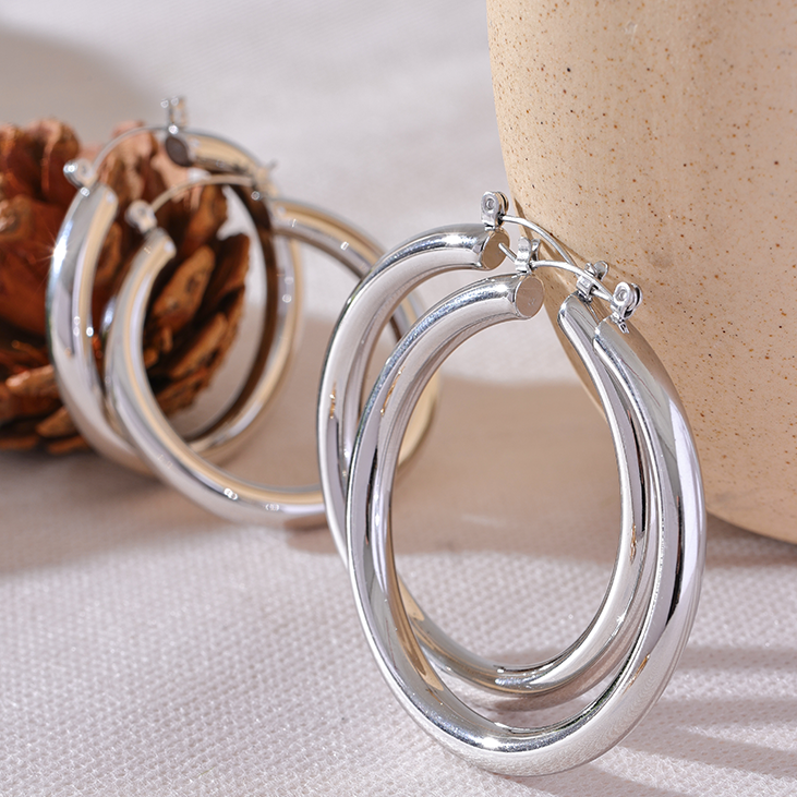 Silver hoop earrings on a textured surface with a neutral background