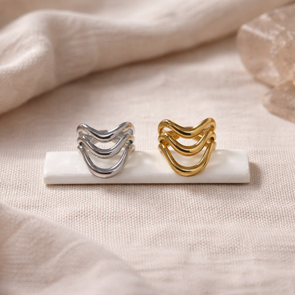 Gold and silver rings on a marble stand with a soft beige background