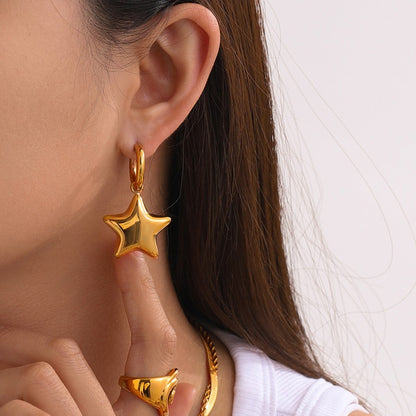 Gold star-shaped earring worn by a person with a neutral background