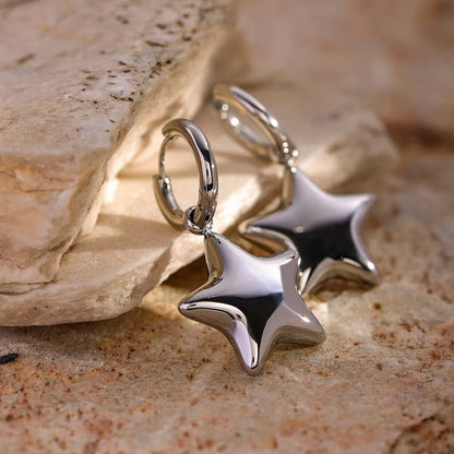 Silver star-shaped earrings on a stone surface