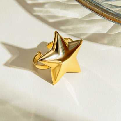 Gold star-shaped ring on a textured beige surface