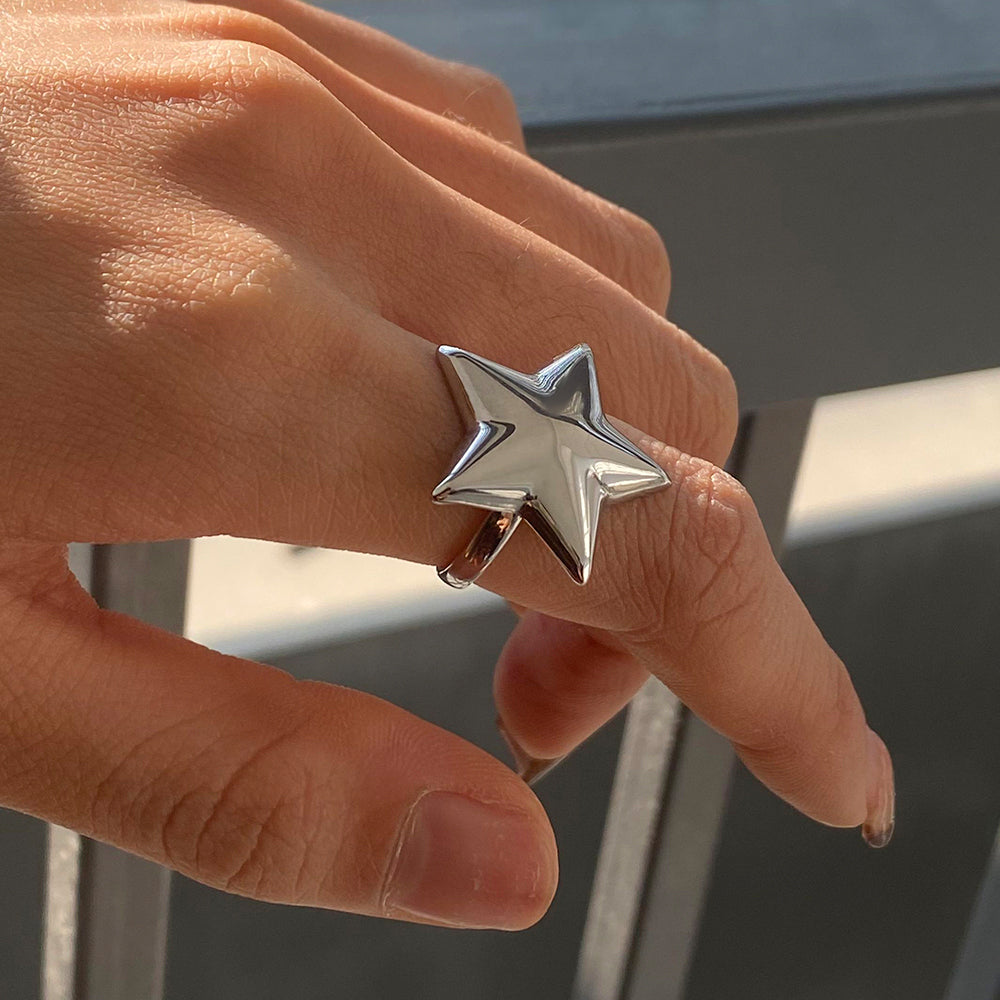 Hand wearing a silver star-shaped ring with a blurred background