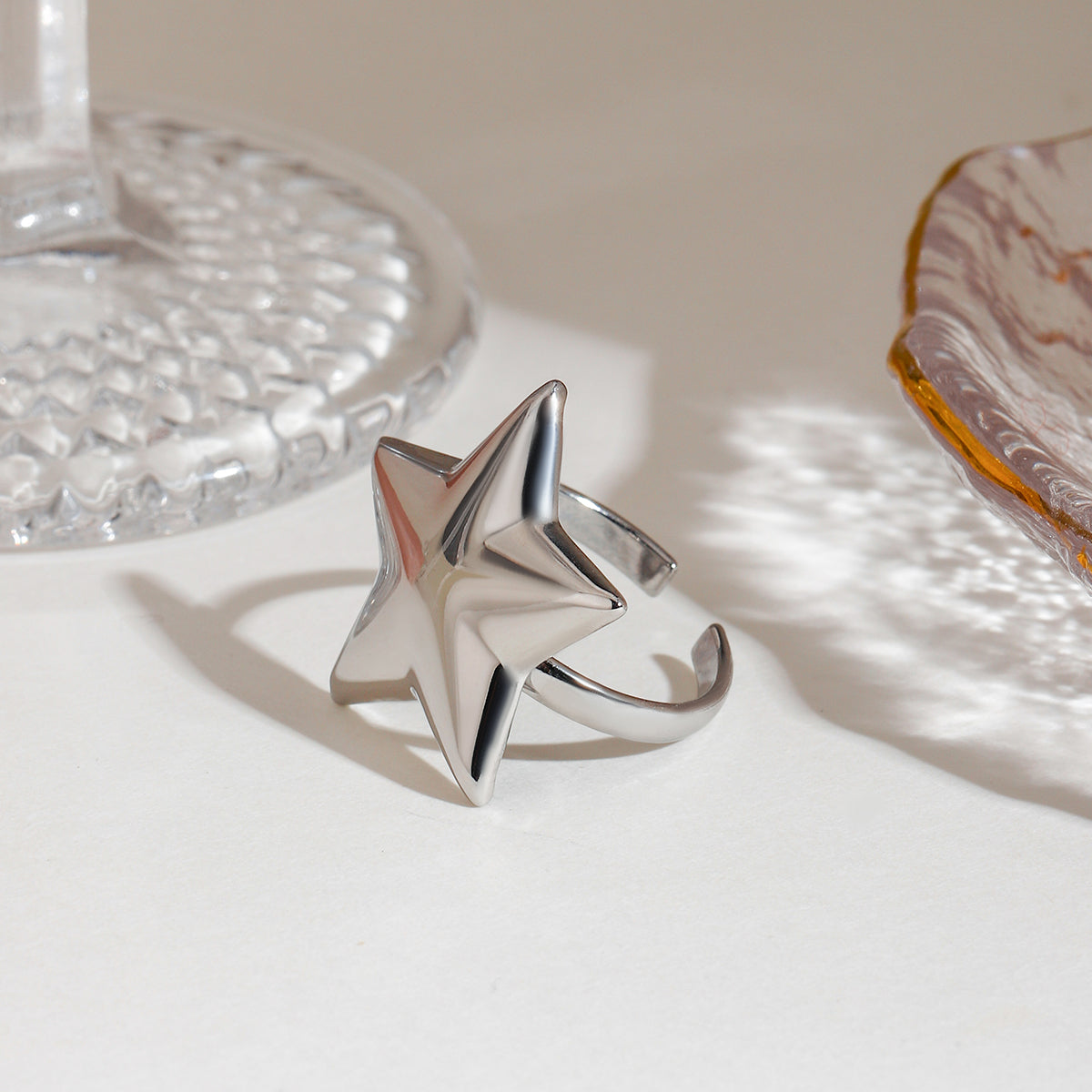 Silver star-shaped ring on a textured surface with a neutral background