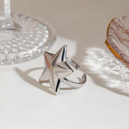 Silver star-shaped ring on a textured surface with a neutral background