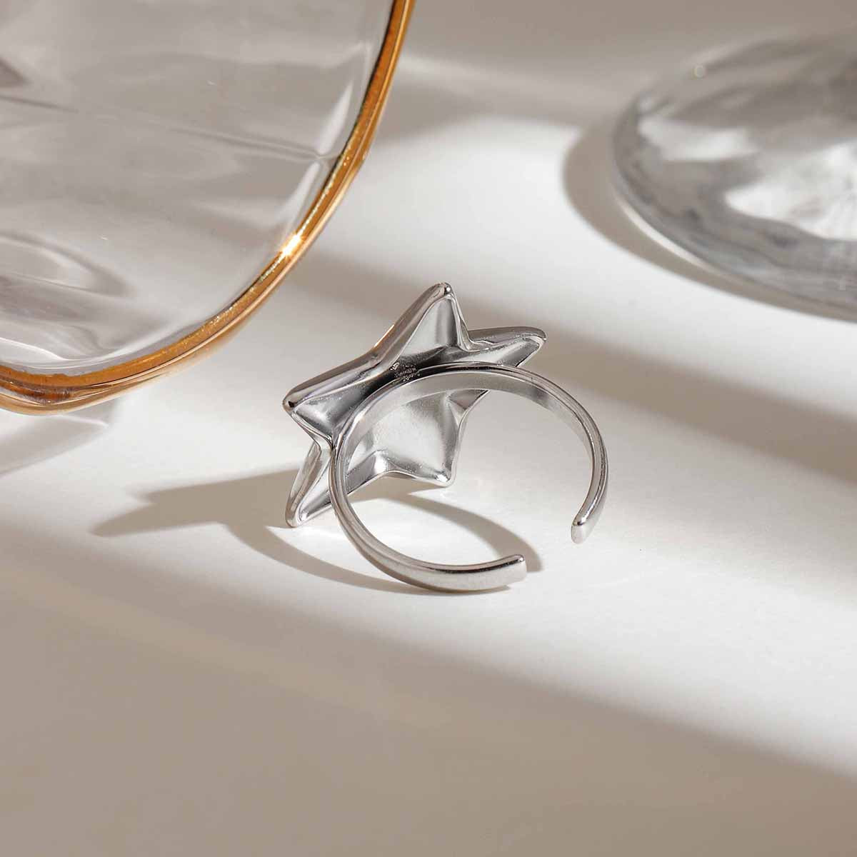 Silver ring with star design on a reflective surface