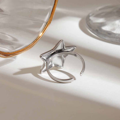 Silver ring with star design on a reflective surface