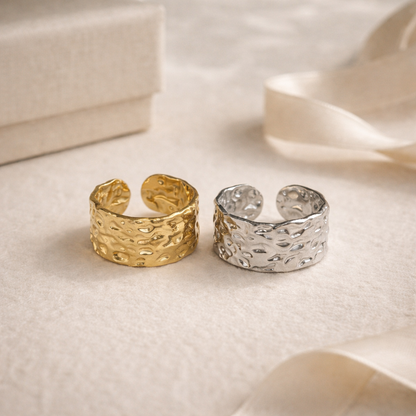 Gold and silver textured rings on a soft fabric background