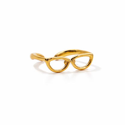 Gold eyeglass-shaped ring on a white background