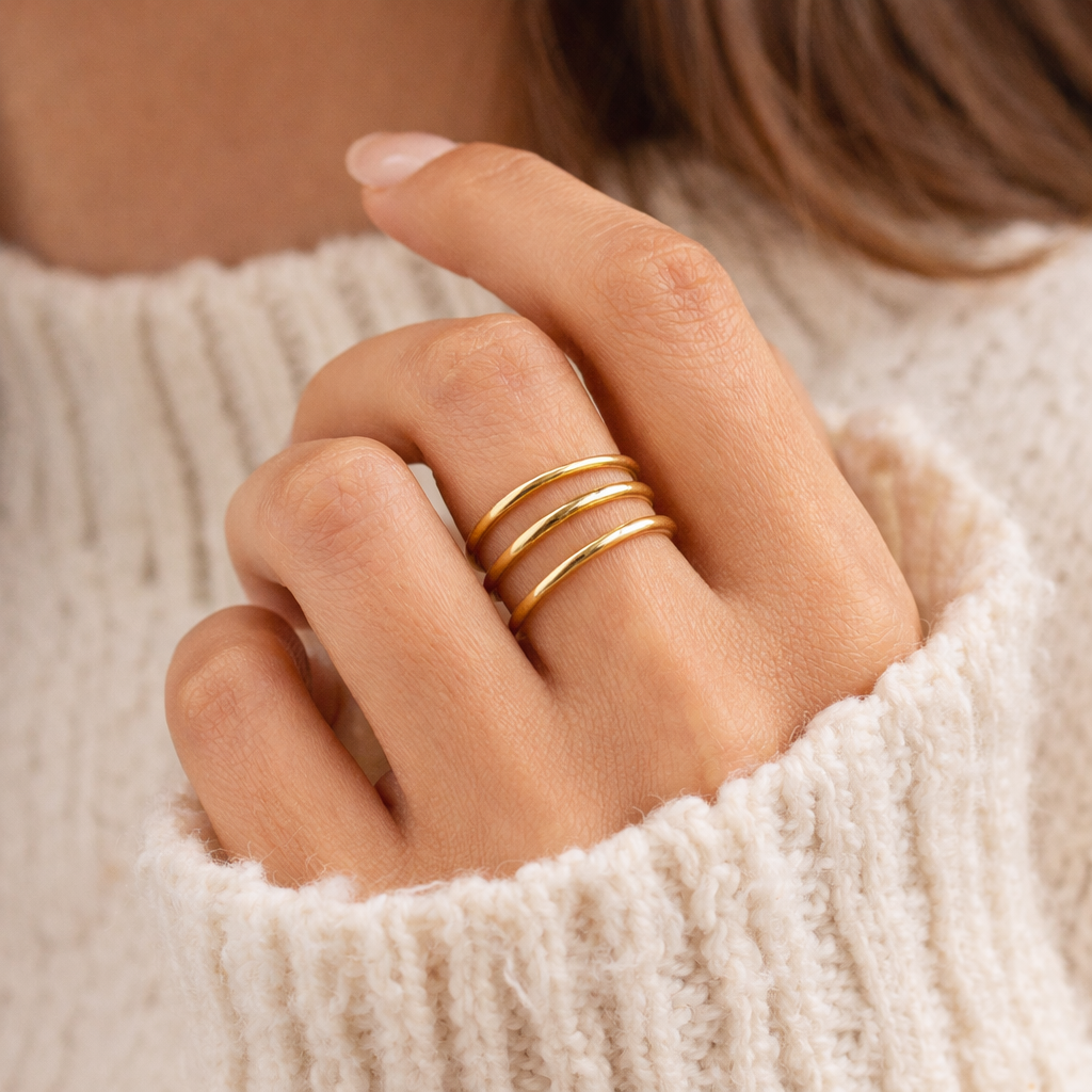 minimalist gold ring on persons hand wearing cozy sweater