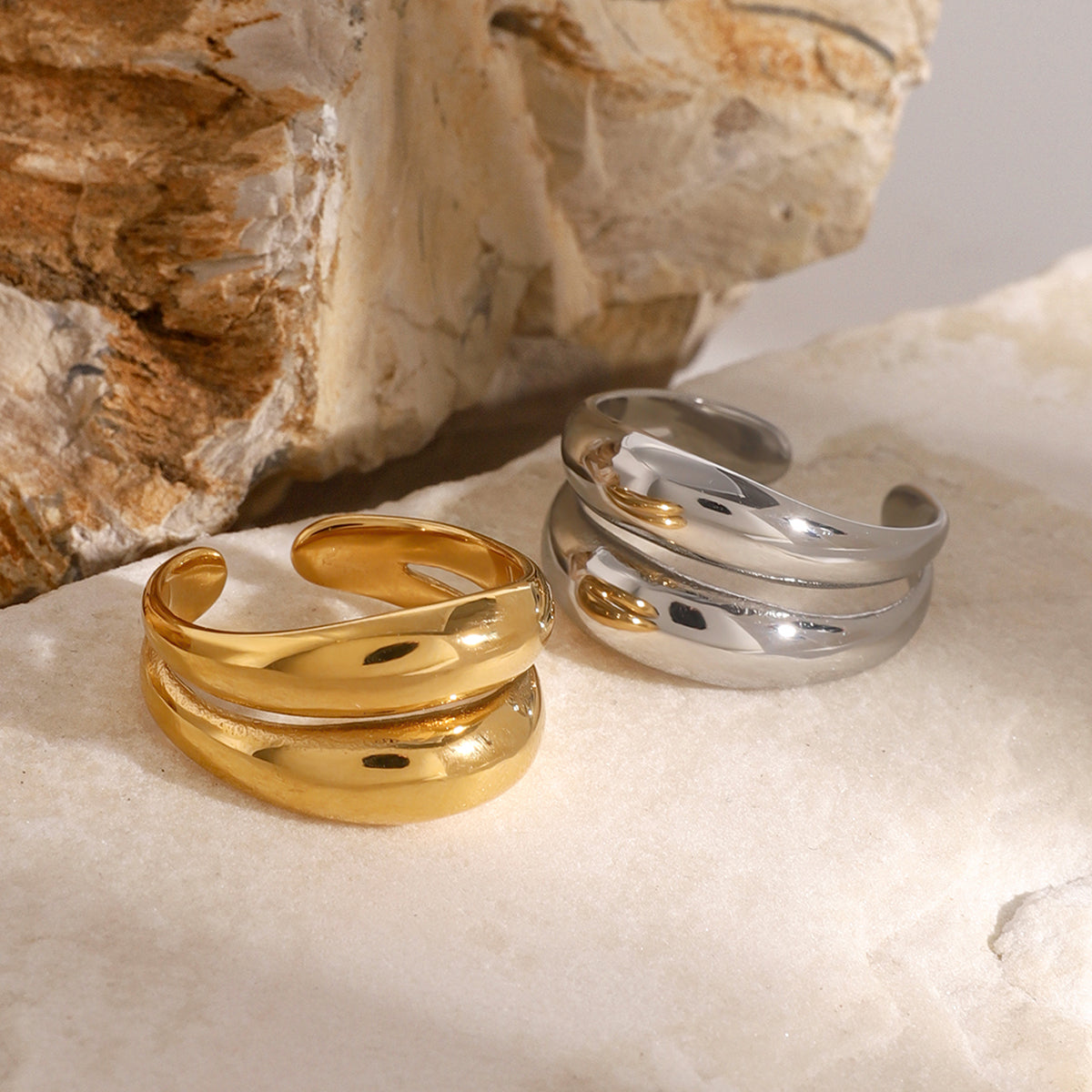 Gold and silver stainless steel rings on a textured stone surface